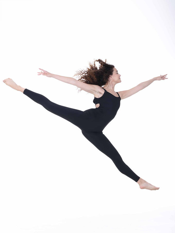 Danseuse en plein saut portant un unitard negro à dos croisé – movimiento aérien en tenue de danse Sway.