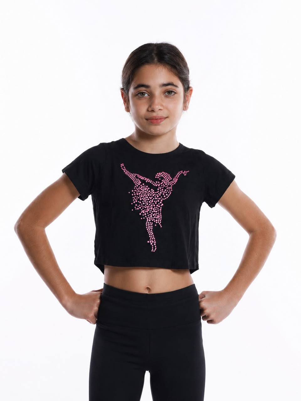 Jeune fille portant un crop top de danse noir à manches courtes orné d’une ballerine en strass roses, associé à un legging noir pour l’entraînement de danse.