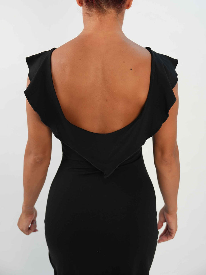 Mujer portant une vestido negroe de baile latino sin mangas, avec encolure volantée et ourlet asymétrique, associée à des medias résille et des zapatos de danza ornées. Tenue elegante et fluido, parfaite pour la salsa ou le ballroom. - vue de l&