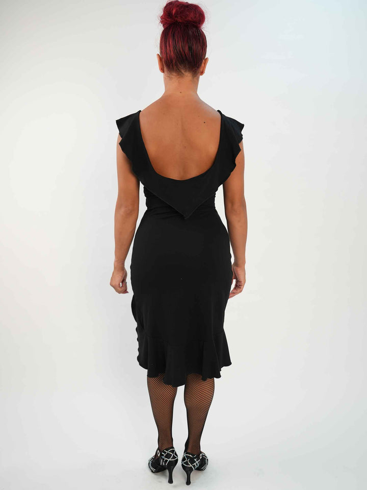 Mujer portant une vestido negroe de baile latino sin mangas, avec encolure volantée et ourlet asymétrique, associée à des medias résille et des zapatos de danza ornées. Tenue elegante et fluido, parfaite pour la salsa ou le ballroom. - vue de l&