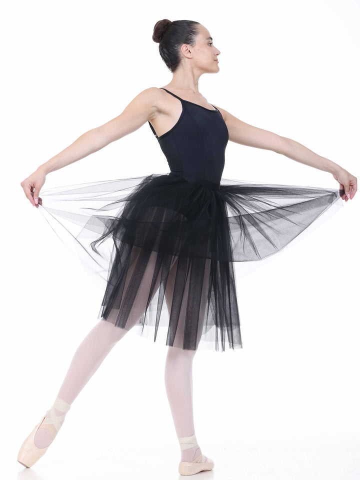 Danseuse en tutu romantique negro effectuant une pose classique – falda longue en tul fluido pour ballet.